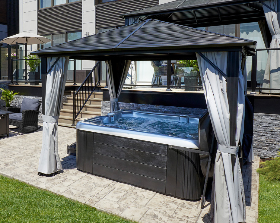A Trevi Sky spa nestled under a gazebo, illuminated at night, creating a cozy and private retreat in an urban backyard.