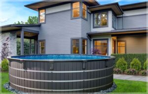 A Trevi Industria above-ground pool sits beside a modern house with large windows, showcasing its contemporary design and ability to enhance outdoor living spaces